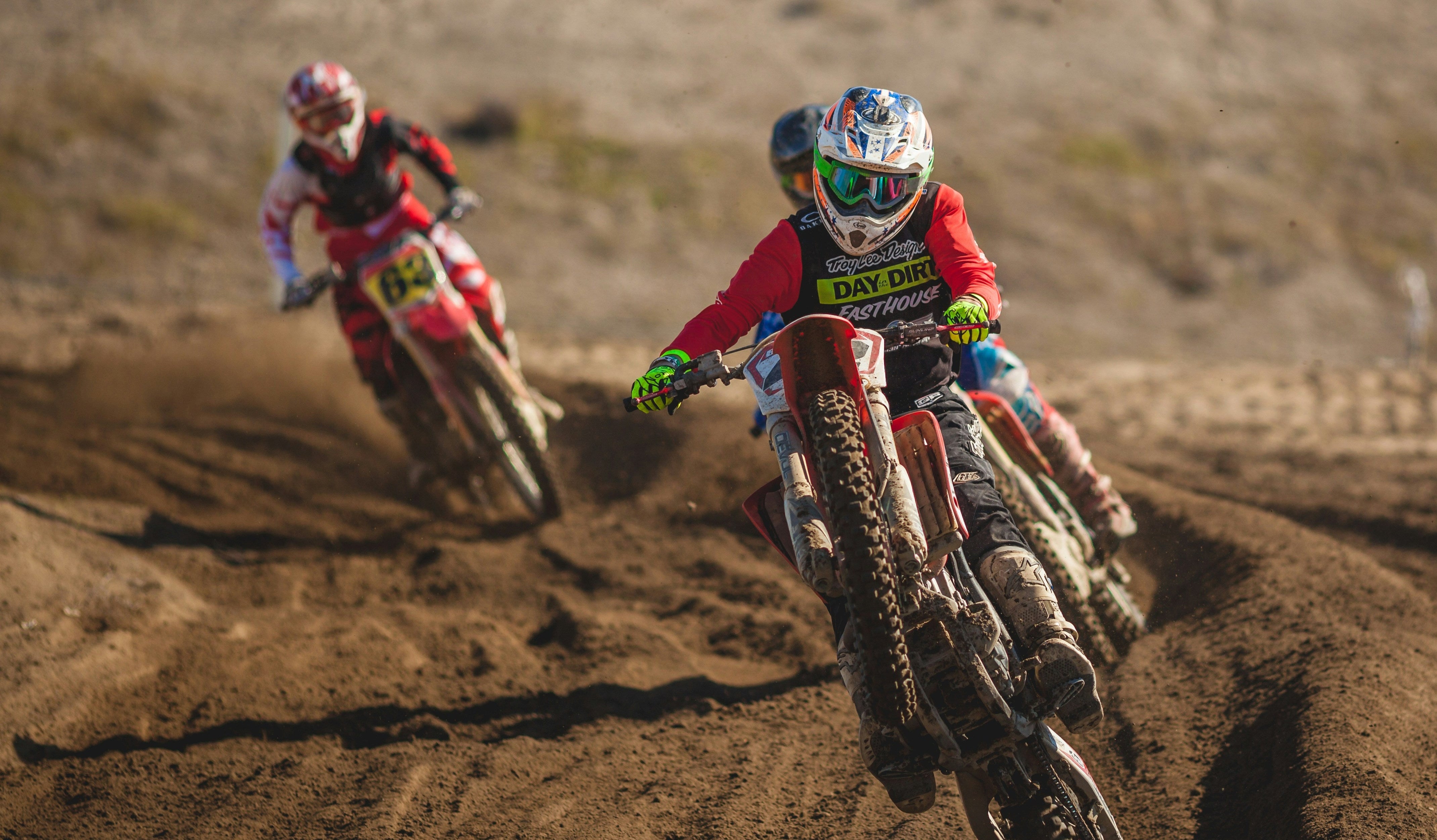 Two motocross riders racing on a dirt track with blurred background